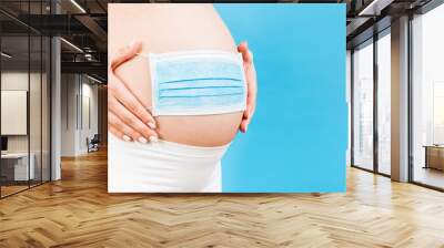 medical mask on the belly of a pregnant girl. hild protection. Concept of coronavirus, covid-19, quarantine Wall mural