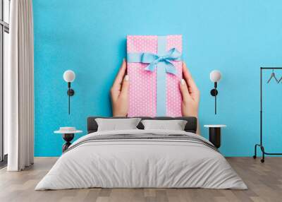 Woman arms holding gift box with colored ribbon on blue table background, top view and copy space for you design Wall mural