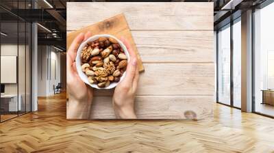 Woman hands holding a wooden bowl with mixed nuts Walnut, pistachios, almonds, hazelnuts and cashews. Healthy food and snack. Vegetarian snacks of different nuts Wall mural