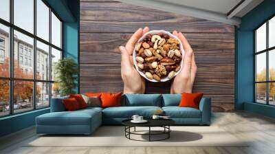 Woman hands holding a wooden bowl with mixed nuts Walnut, pistachios, almonds, hazelnuts and cashews. Healthy food and snack. Vegetarian snacks of different nuts Wall mural