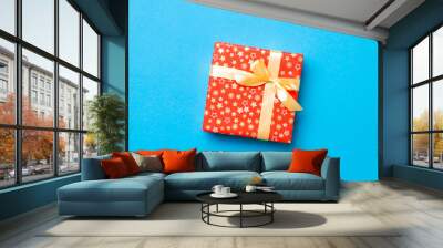 wrapped Christmas or other holiday handmade present in paper with Gold ribbon on blue background. Present box, decoration of gift on colored table, top view with copy space Wall mural