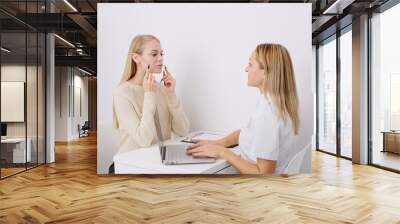 Consultation in cosmetology clinic. Female professional beauty doctor talking with pretty young female. Wall mural