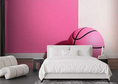 pink basketball rests against two toned pink and white wall on wooden floor, creating vibrant and playful atmosphere Wall mural