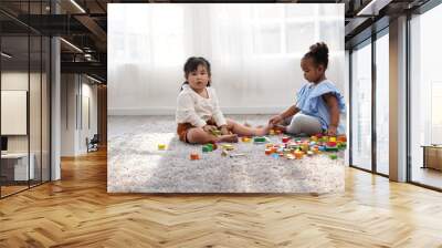 Two female kid playing in the home school with wooden block as creative learning. African girl and Asain girl are playing together with fun. Wall mural