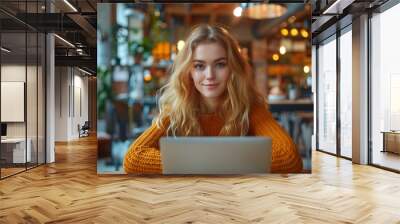 A young startup employee looking straight ahead from her laptop. Wall mural