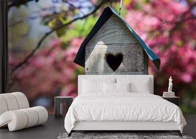 Birdhouse with heart shaped opening  hanging in an apple tree in spring Wall mural