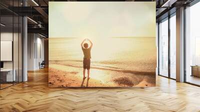 Boy on the beach making a heart shape with his hands Wall mural