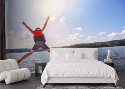 Kids jumping off a boat into the lake. Focus on boys legs and boat, some motion blur. Wall mural