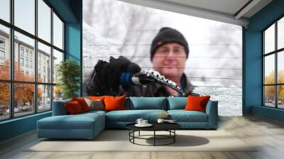 Man scraping snow and ice from car window , shot through wet windshield, Wall mural