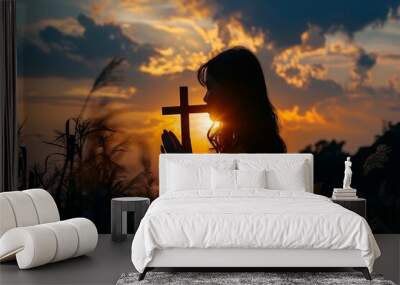 Silhouette of woman praying with cross in hand at sunset, Christian concept. Silhouettes and hands with cross symbol isolated on background. photography shot using Canon EOS R5 f/20 ISO480 Wall mural