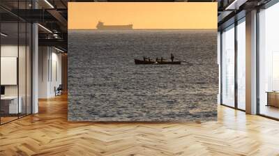 Rowers rowing in the sea with a large ship in the background. Industry. Wall mural