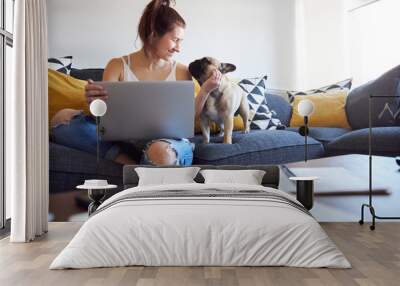 Female working on laptop with pet dog on sofa. Wall mural