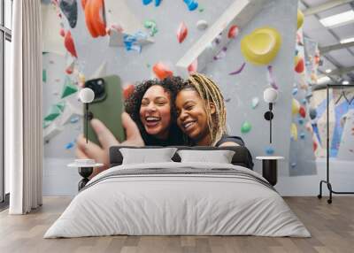 Two Smiling Female Friends Posing For Selfie By Climbing Wall At Indoor Activity Centre Wall mural