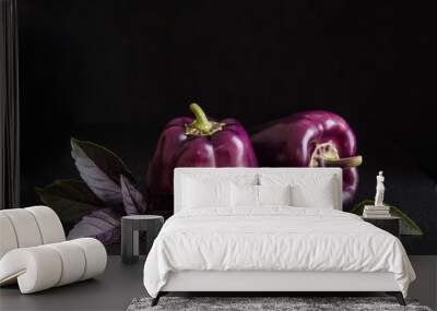 Fresh vegetable. Dark purple peppers with leaves of basil on black stone, black background Wall mural