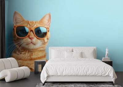 A cat wearing sunglasses and standing in front of a blue wall Wall mural