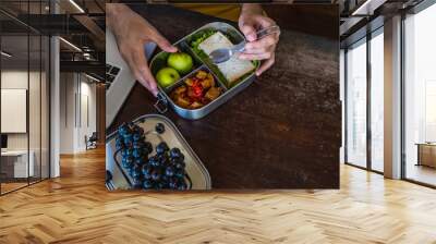 Close up of man hands at desk with a laptop at home or in office with healthy vegan meal in reusable stainless steel lunch box. Healthy lifestyle, zero waste and sustainable plastic free lifestyle Wall mural