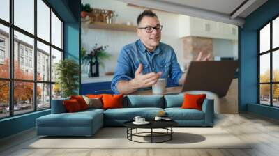 Happy adult man having a video call with a laptop at home Wall mural