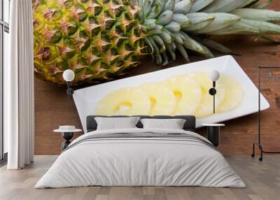 Pineapple slices on the plate on wooden table Wall mural