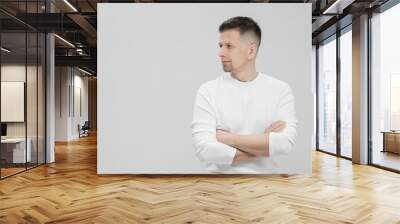 Futuristic handsome bearded brunet man 40s years in white clothes on a white background with folded arms, portrait. God, teacher and boss. Wall mural