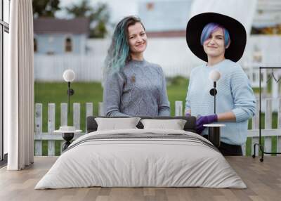 Two young women in the background of a garden with gloves and tools with a field of beds Wall mural