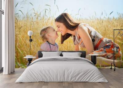 Happy young mother with little daughter on field in summer day Wall mural