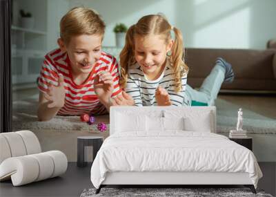 Portrait of two cheerful children laying on the floor and playing with colorful dices Wall mural