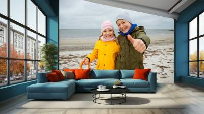 Portrait of two happy teenagers staing on coast of Baltic sea at windy rainy weather Wall mural