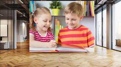 two happy siblings reading interesting book Wall mural