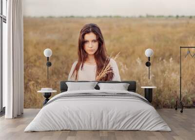 Young girl with long brown hair holds a bundle of ears  Wall mural