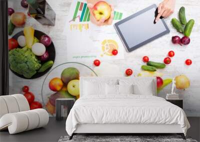 Close-up of a young adult woman informing herself with a tablet PC about nutritional values of fruits and vegetables.. Wall mural