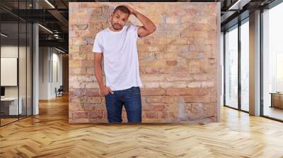 Portrait of a serious handsome young man in a white tshirt and blue jeans. Wall mural