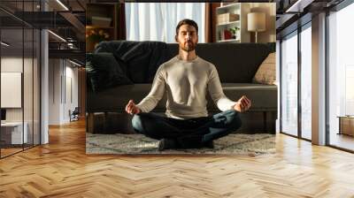 Caucasian man meditating in lotus pose and with closed eyes. Sport and healthy lifestyle concept Wall mural