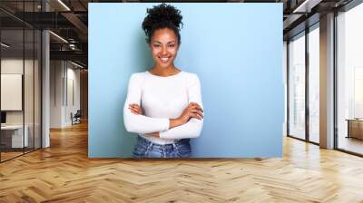 Happy african american woman folded arms while standing over studio blue background- Image Wall mural