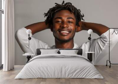 Smiling black man with dreadlocks holding head, wears white sweatshirt against white background Wall mural