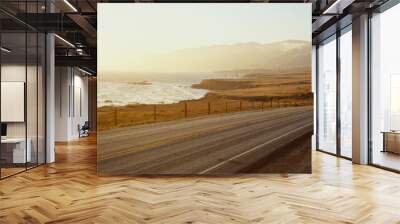 This is Route 1also known as the Pacific Coast Highway. The road is situated next to the ocean with the mountains in the distance. The road goes off into infinity into the sunset. Wall mural