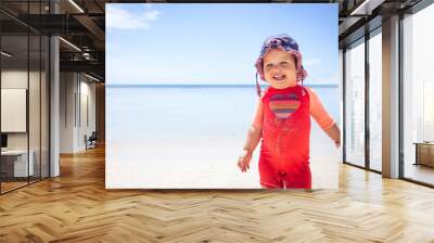 Cheerful cute happy smiling baby kid sun protective suit beach blue sea sky sunscreen background copy space  Wall mural