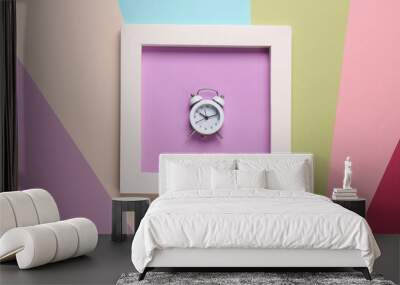 Alarm clock in white square frame on colored background. Aesthetic minimal still life. Conceptual photo. Modern art. Top view Wall mural