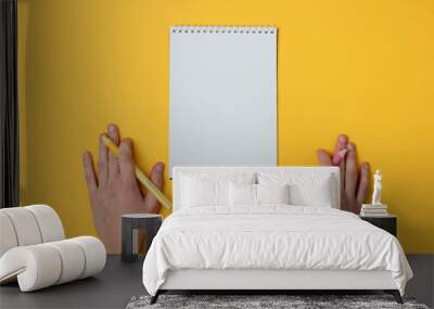 Ambidextr two female hand with pens and notebook on yellow background. Girl's diary. Top view Wall mural