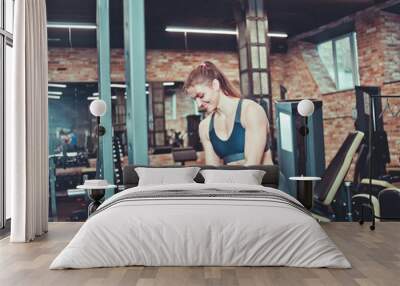 Athletic woman putting disk to barbell in gym Wall mural