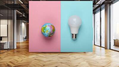 Eco concept. LED light bulb and globe on a blue-pink pastel background. Top view. Wall mural