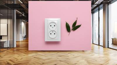 Eco concept. Power Energy Economy. Save the planet. Double power socket, green leaves on pink pastel background. Studio shot Wall mural