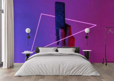 Female hand holds tv remote. Creative pop art pink blue neon color. Trendy gradient illumination. Night light Wall mural