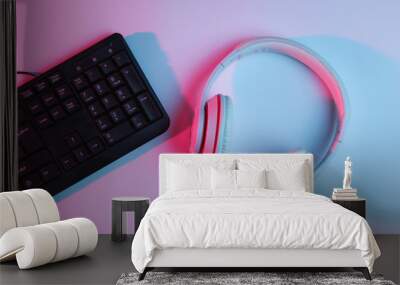 Gaming equipmen. Keyboard and headphone with neon gradient pink-blue light. Music concept. Computer game competition. Top view Wall mural