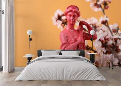 Godness sculpture and Beautiful flowering branches on orange background. Wall mural