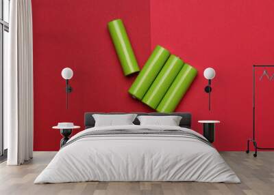 Green AA batteries on a red background Wall mural