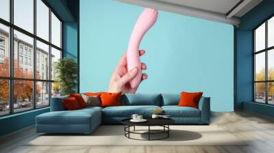 hand holding Sex toy for women on blue background. Wall mural