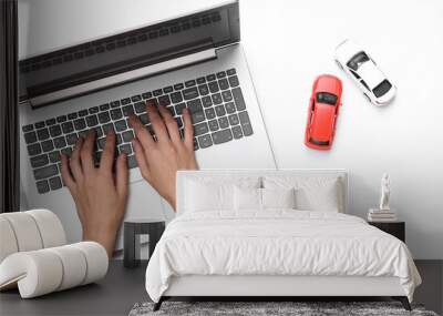 Hands are typing on a laptop keyboard, and toy cars on a white background. Search auto concept Wall mural