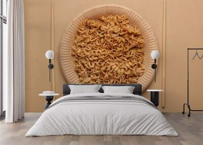 Instant noodles in cardboard plate with chopsticks on beige background. Top view Wall mural