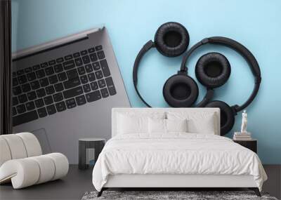 Laptop and two pairs of black wireless stereo headphones on a blue background Wall mural