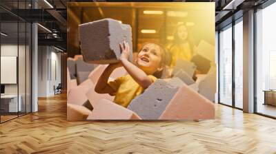 Little happy girls play and have fun in a dry pool with paralon cubes in a children's entertainment center Wall mural